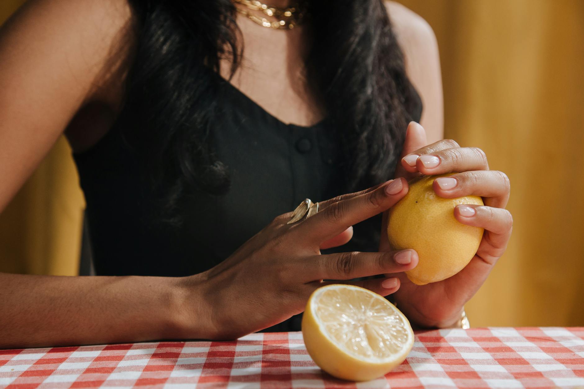 Hand holding a lemon against soft pink background, symbolizing fresh conversations about pleasure