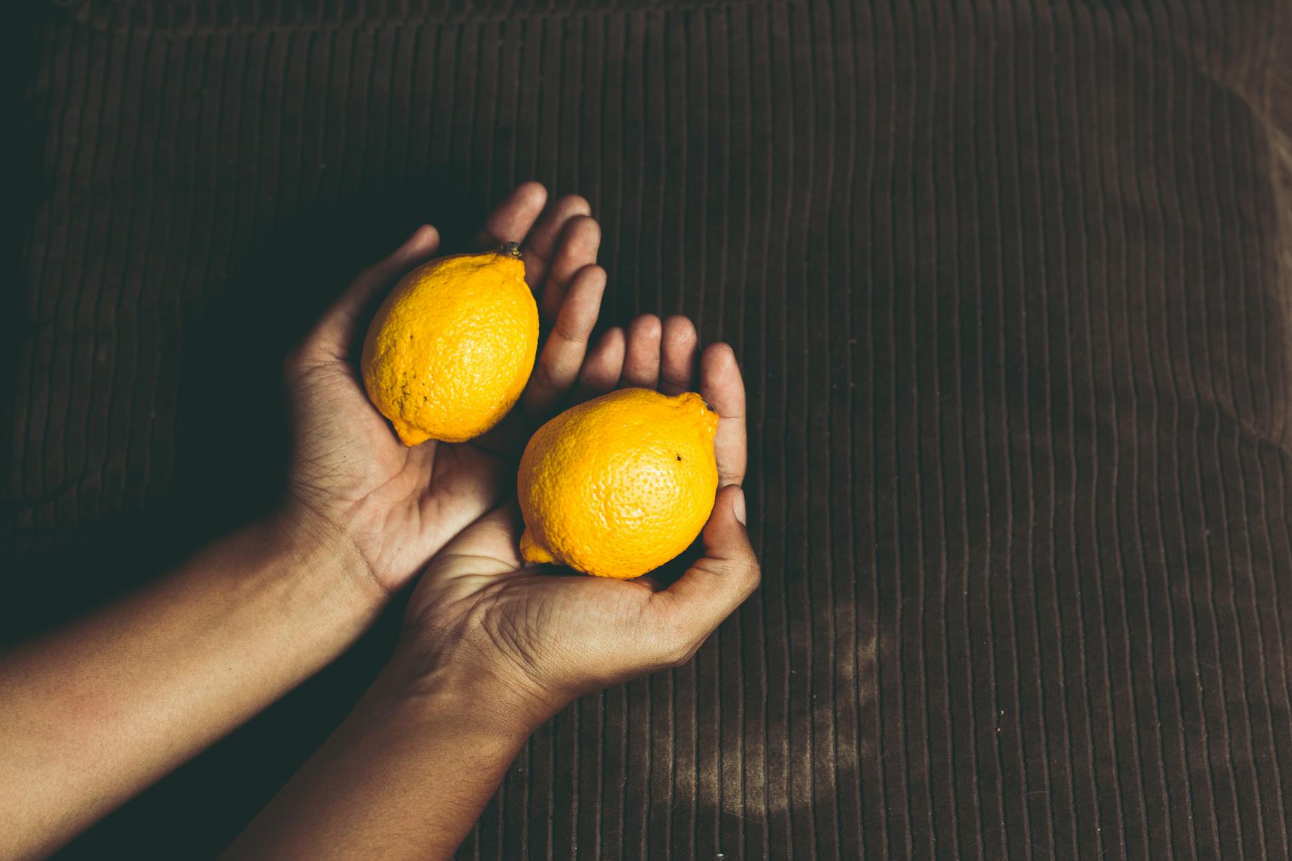 Two fresh lemons held in cupped hands, symbolizing care and reclamation
