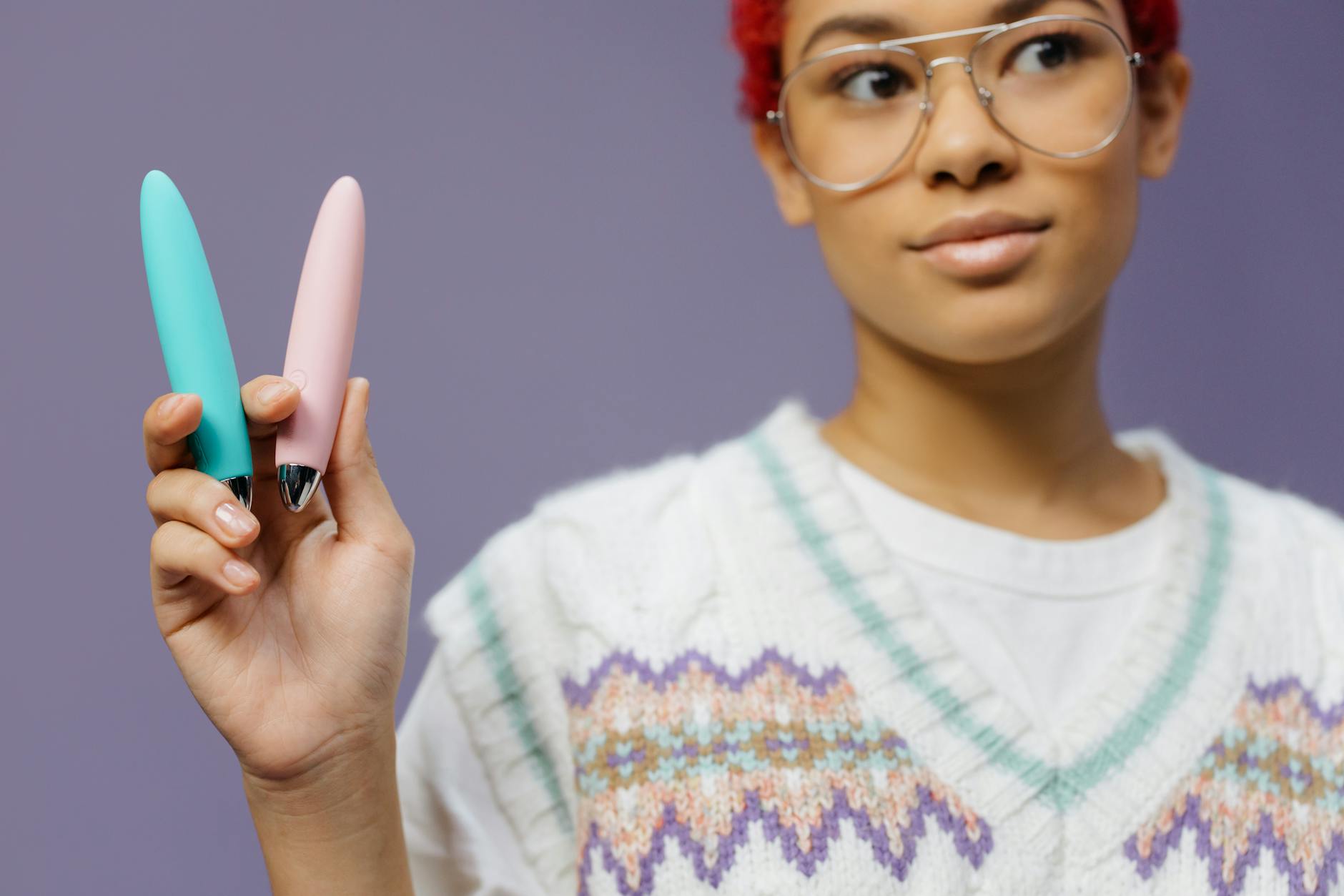 Person holding a colorful lemon clitoral vibrator against a purple background