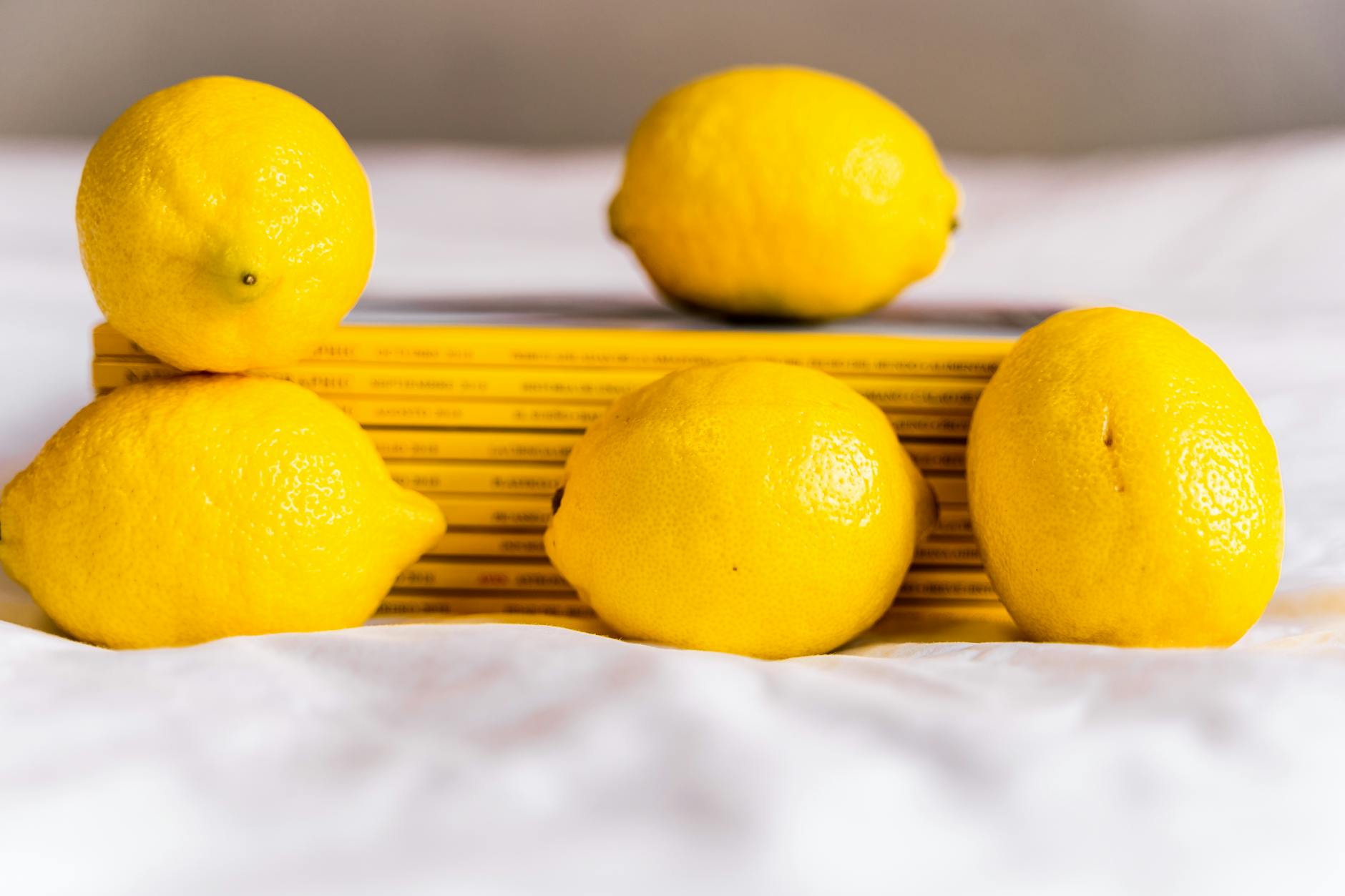 Fresh yellow lemons arranged with stacked books on a white surface